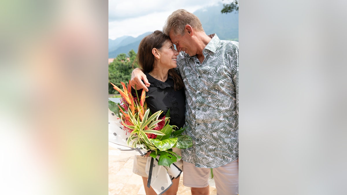 Gerry Turner and Theresa Nist canoodling as she holds a bouquet of flowers.