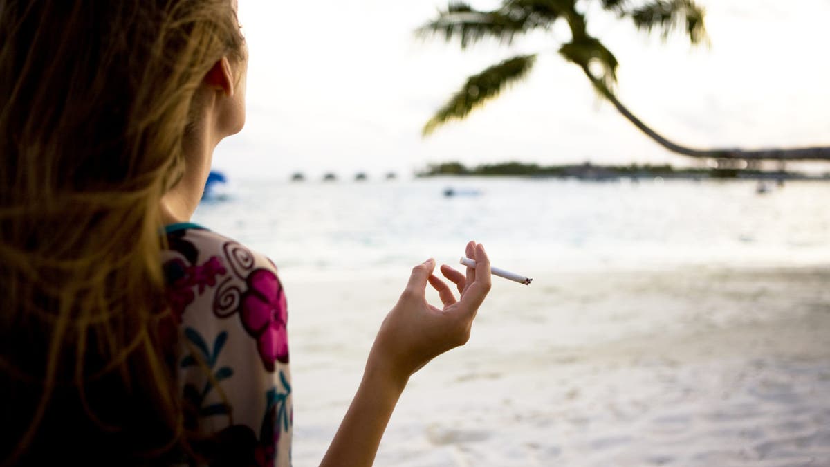 back of woman smoking on beach
