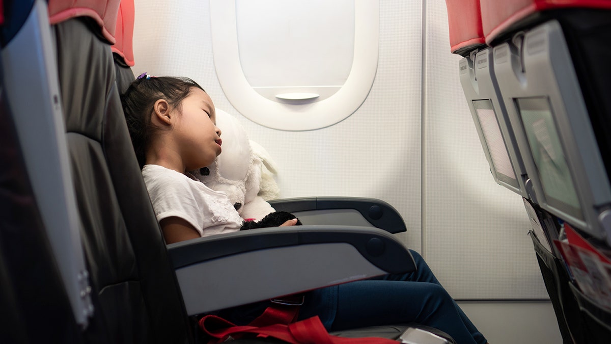 A girl sleeps by herself on a plane.