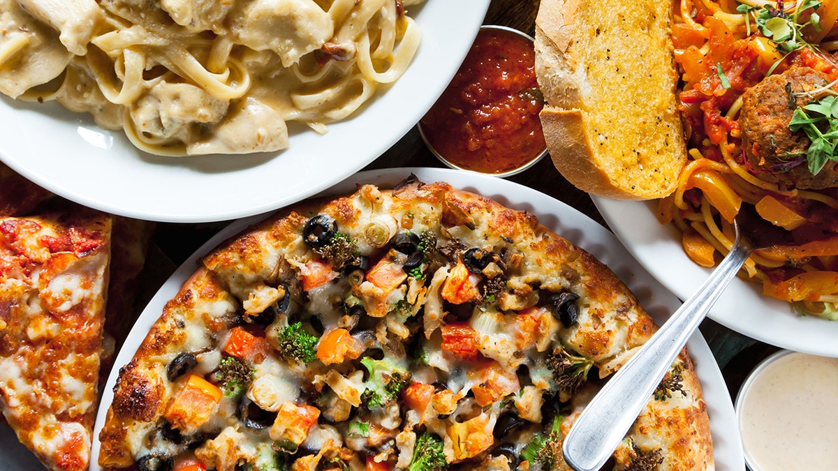 Overhead shot of gluen-packed dinner spread includingpizza, spaghetti, meatballs, and chicken alfredo.