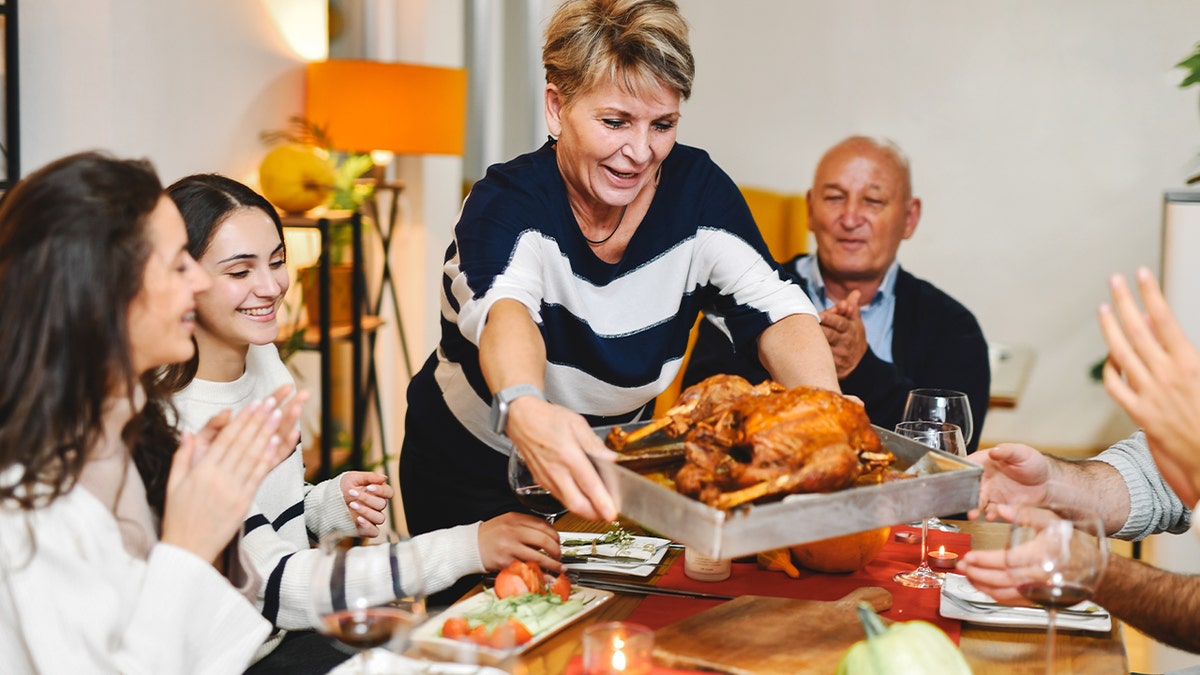 Woman presenting Thanksgiving turkey at table