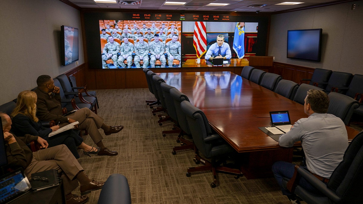 Pete Hegseth sits at a table during a video call with soldiers.