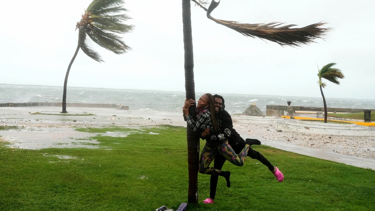 couple joking around on beach in jamaica in hurrican with palm trees