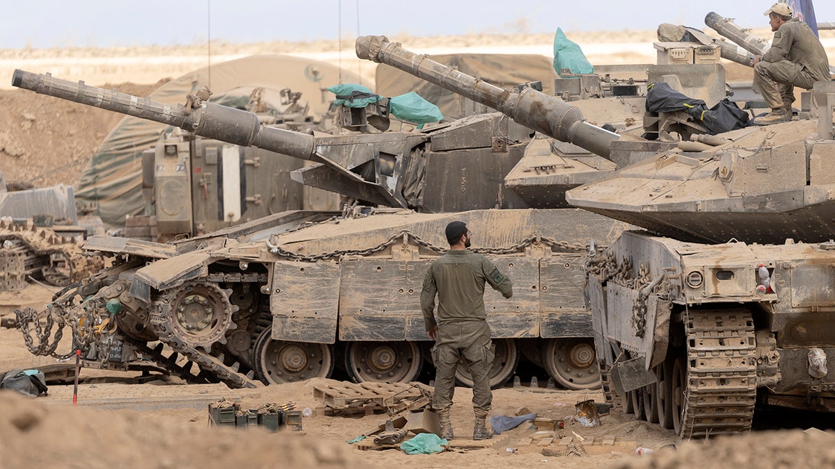 Israeli soldiers stand next to tanks near Gaza Strip