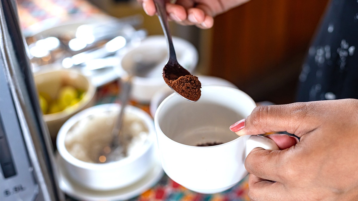 Person putting instant coffee in cup