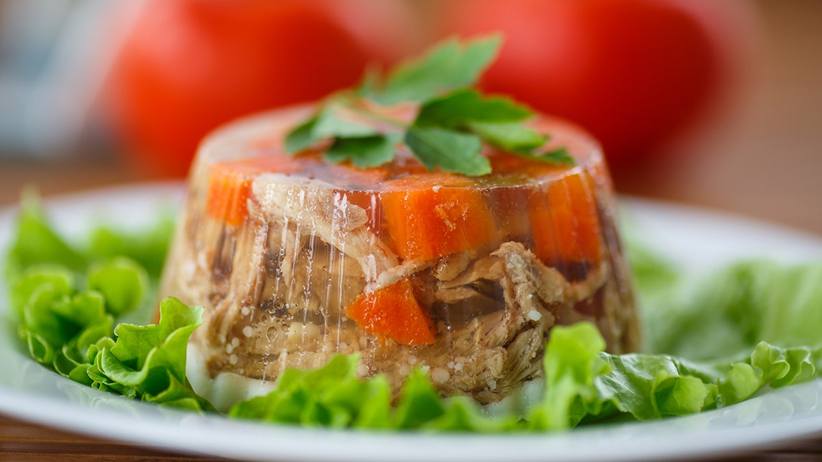 Jellied meat with lettuce on a plate, seen garnished with greens.
