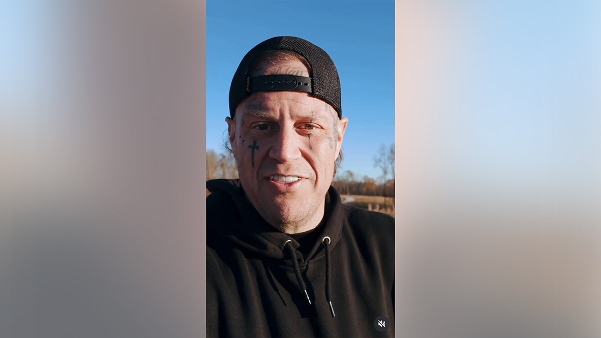 Jelly Roll in a black outfit and hat without his beard