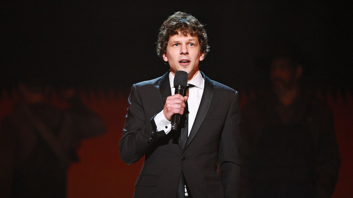 Jesse Eisenberg holds a mic and talks