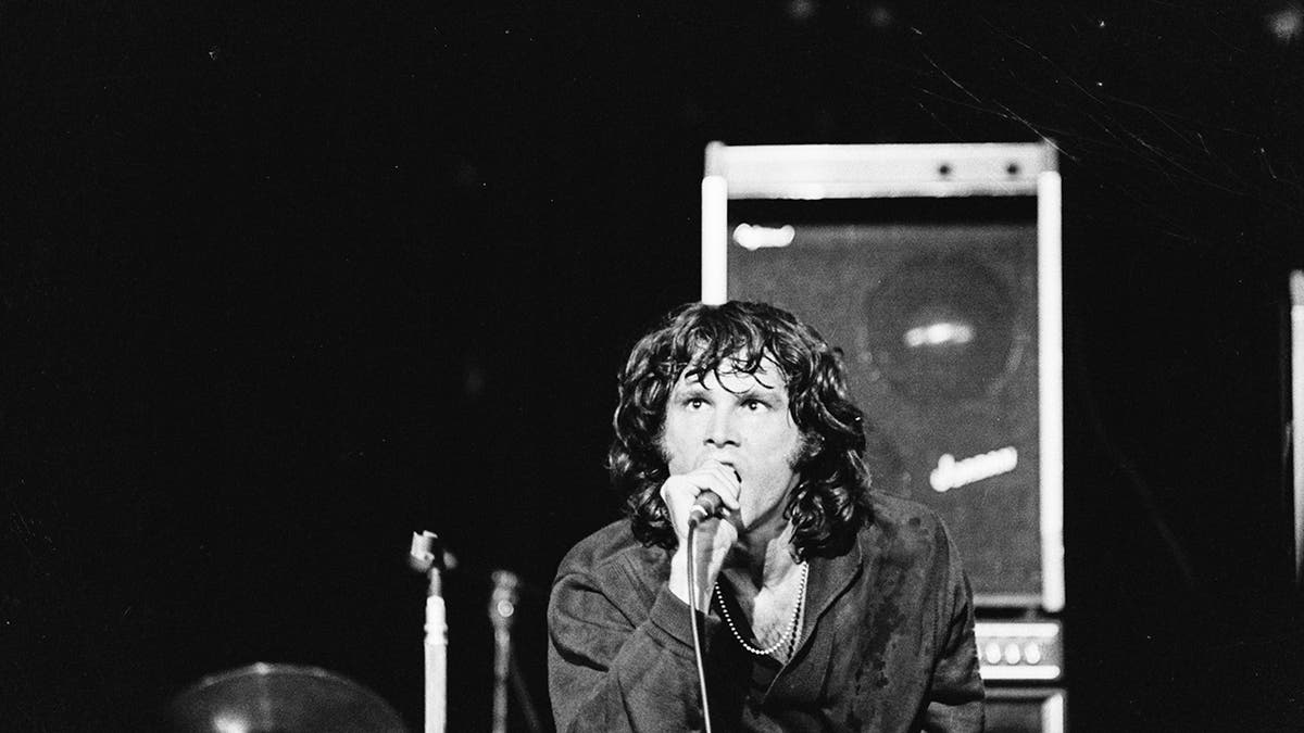 A close-up of Jim Morrison singing on stage with widened eyes.