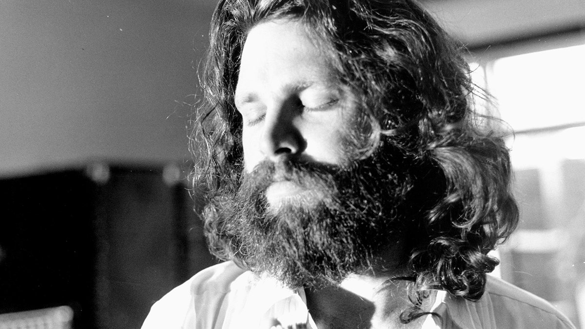 A close-up of Jim Morrison with his eyes closed.