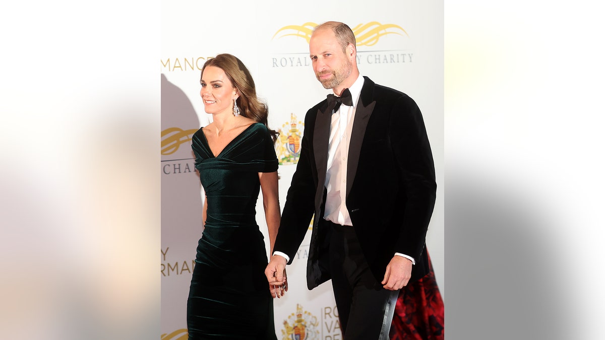 Prince William and Kate Middleton walking together on the red carpet in formal wear.