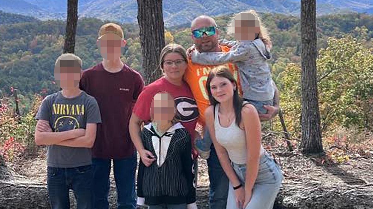 2 boys, 3 girls and two adults pose for a family photo in the mountains
