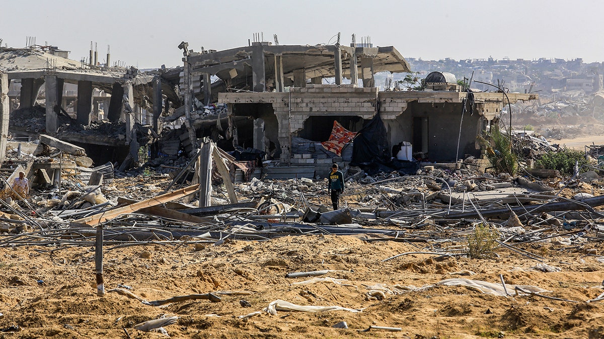 Person walks among damage and debris in Khan Younis in the Gaza Strip