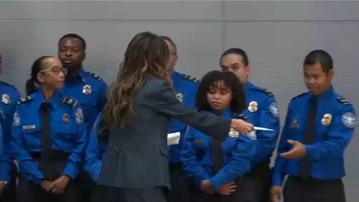 Kristi Noem le entrega un cheque de bonificación a un oficial de la TSA