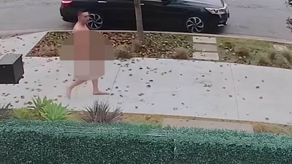 A naked home invasion suspect walks down a sidewalk