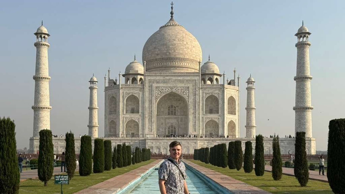 Traveler stands in front of the Taj Mahal’s white marble domes and reflecting pool in Agra, India.