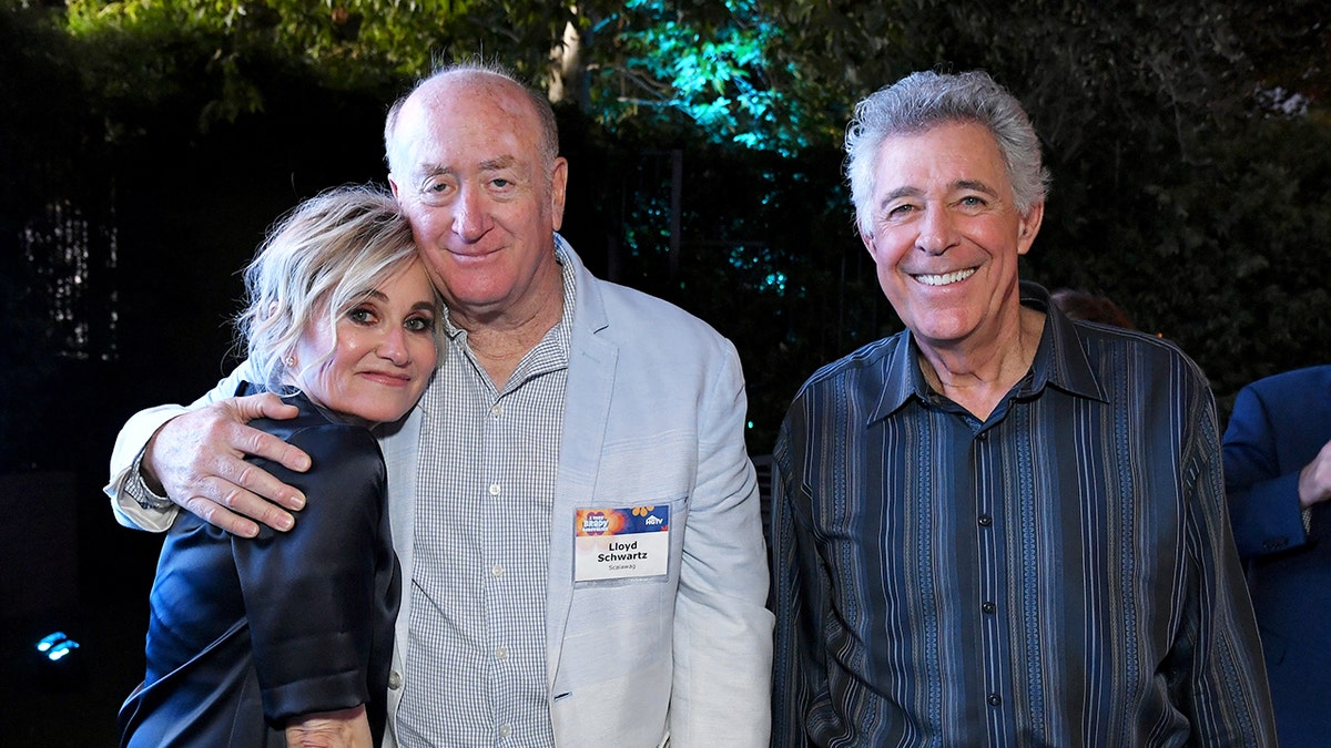 勞埃德·施瓦茨 (Lloyd Schwartz) 擁抱莫琳·麥考密克 (Maureen McCormick),巴里·威廉姆斯 (Barry Williams) 微笑。