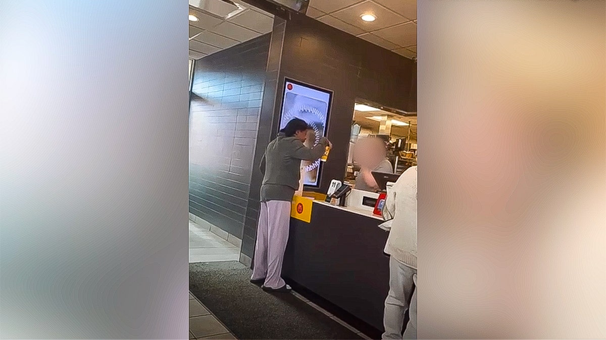 Woman picking up a coffee cup while arguing at McDonald's.
