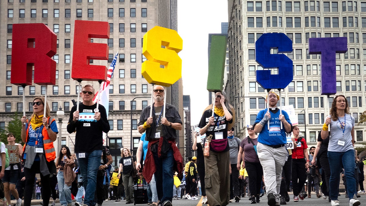 "No Kings' protesters marching with a "RESIST" sign