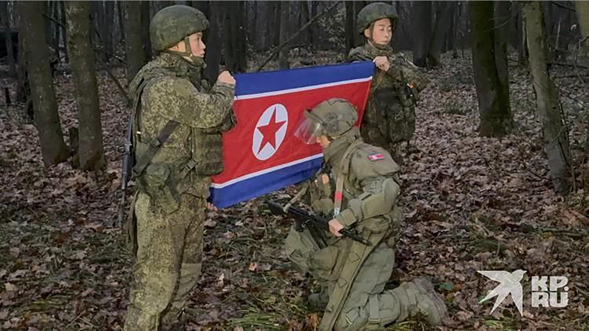 North Korean soldiers pose next to their country's flag