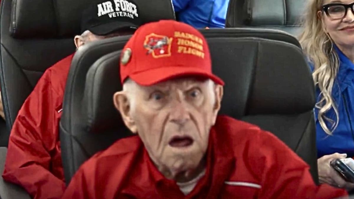 Close-up of veteran in red cap reacting with surprise on Honor Flight