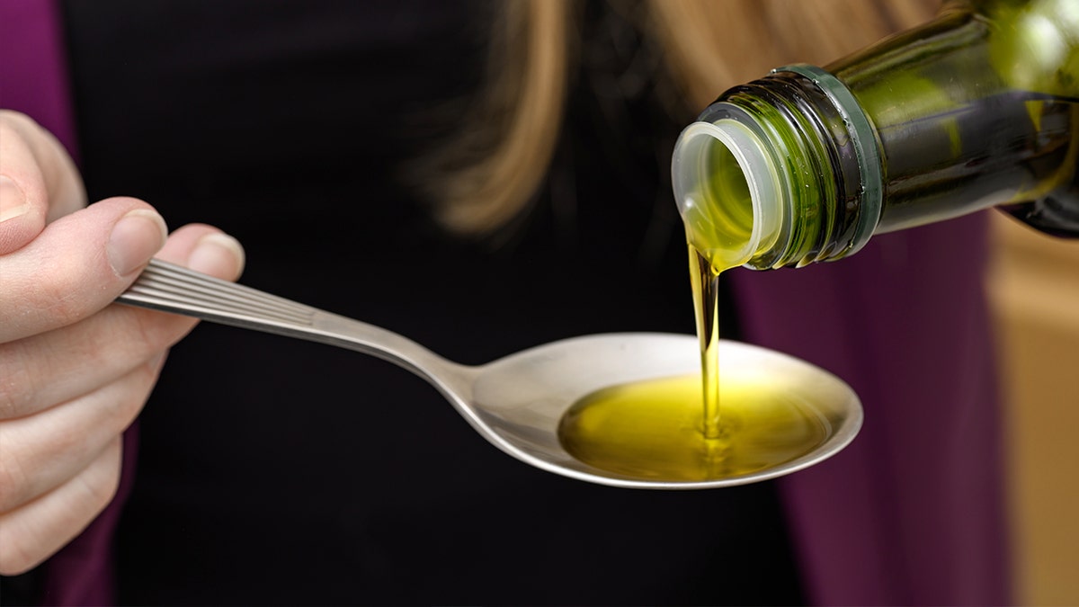 Woman pouring olive oil on spoon
