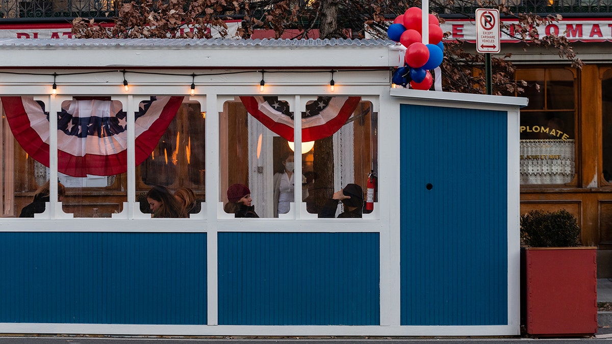 Outdoor dining hut in Washington, D.C., seen outside restaurant painted blue with American flag buntings hanging.