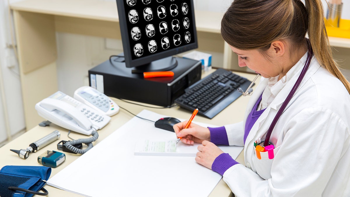 Doctor working, CAT scan picture on monitor