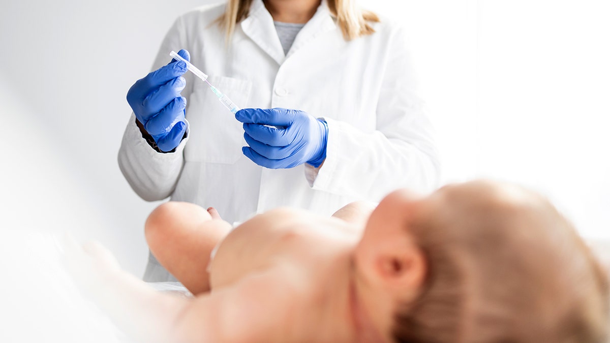 Pediatrician doctor preparing vaccine injection for baby immunisation.