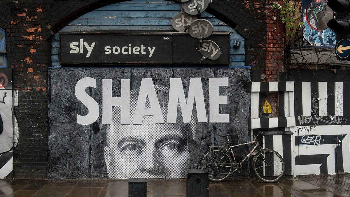A poster of Prince Andrew with a sign that reads "Shame" in the U.K.