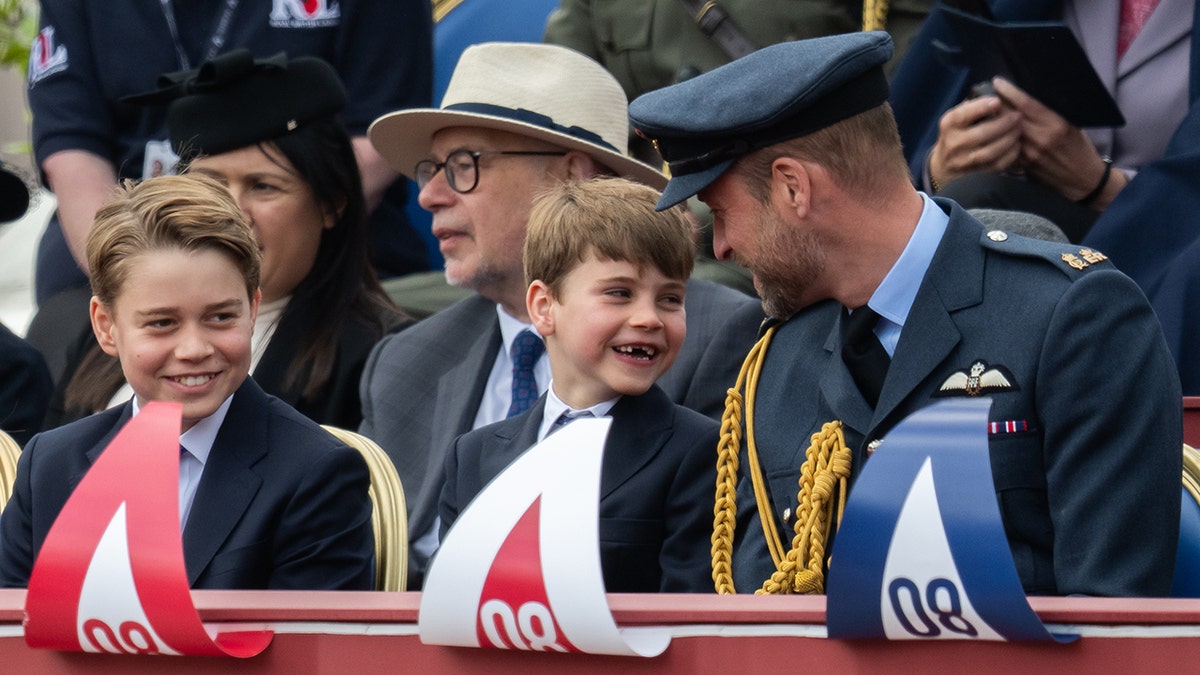 Prince William smiling to a laughing Prince Louis as Prince George grins.