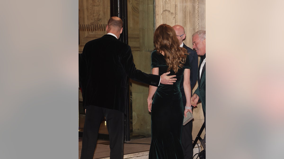 Prince William touching Kate Middleton's back.