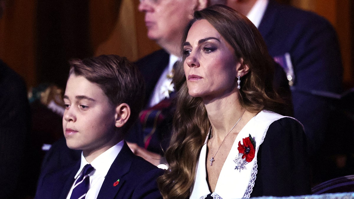 Prince George and Kate Middleton sitting next to each other in dark attire.