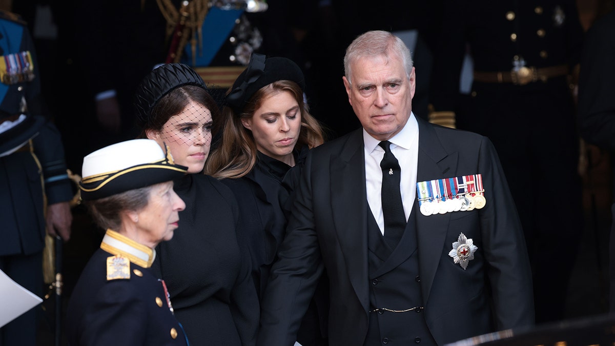 Prince Andrew in a dark suit with medals standing near his daughters and his sister Princess Anne.