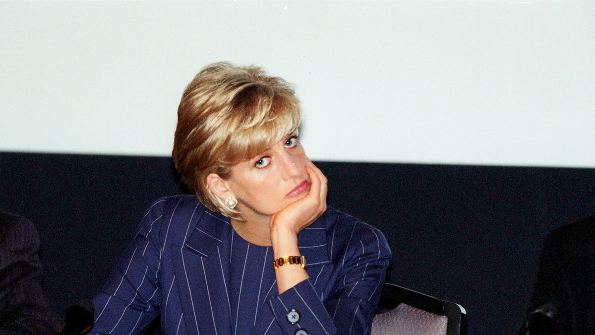 Princess Diana wearing a blue pinstripe blazer looking downcast.