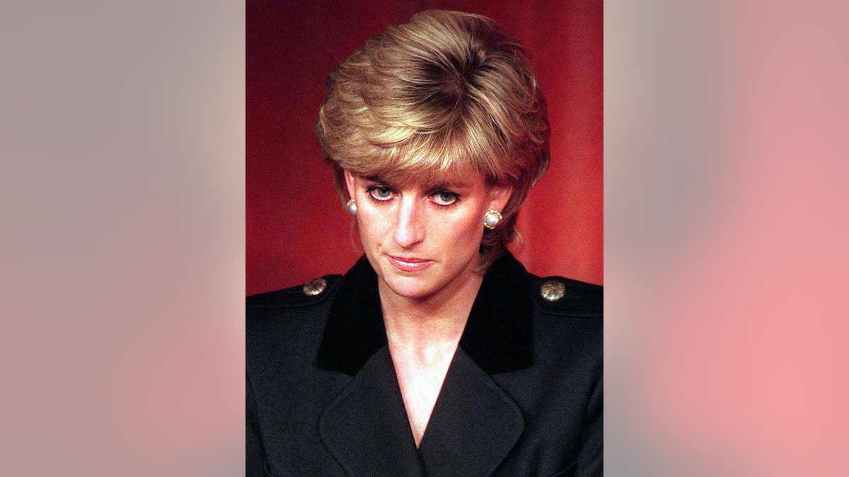 Princess Diana looking sad in a black v-neck.