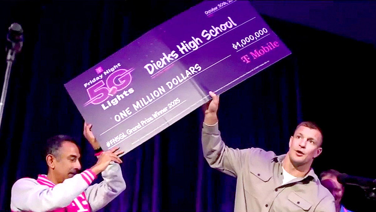 Rob Gronkowski stands with T-Mobile CEO Srini Gopalan while holding a donation check for Dierks High School.