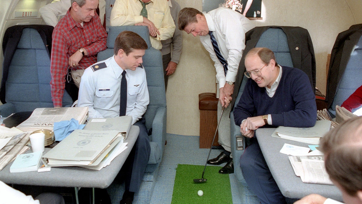 Presidente Reagan colocando uma bola de golfe com Robert McFarlane Jim Kuhn Thomas Dawson Thomas Carter George Shultz Don Regan e Dennis Thomas olhando a bordo do Força Aérea Um observando-o jogar.