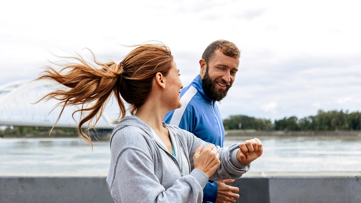 Cheerful couple running together outside