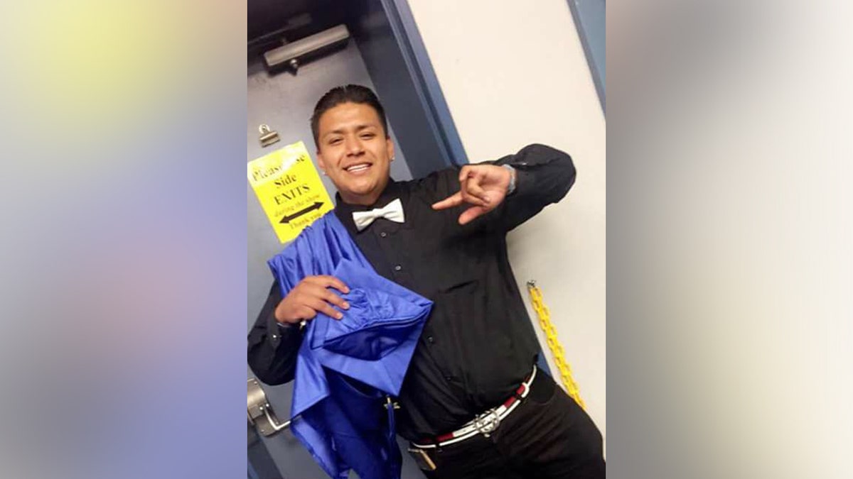 Edu Veliz-Salgado smiles for a picture with his graduation cap in his hand.