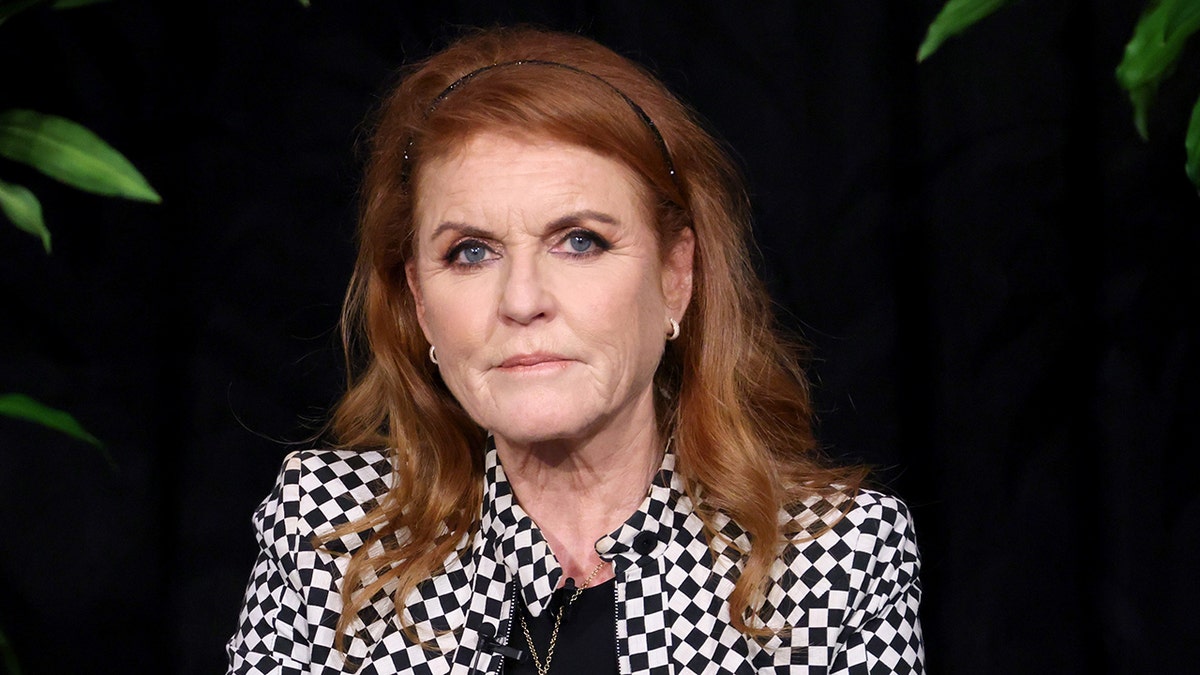 A close-up of Sarah Ferguson looking concerned in a black and white checkered blazer with a black shirt.