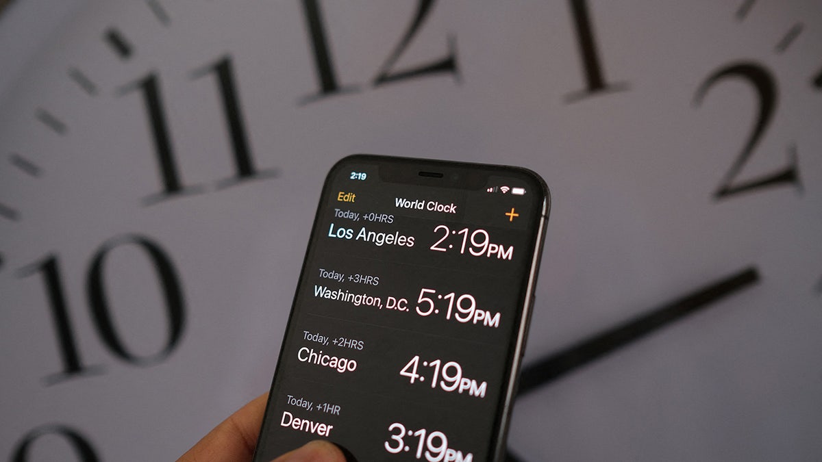A phone user looks at their clock settings on their phone