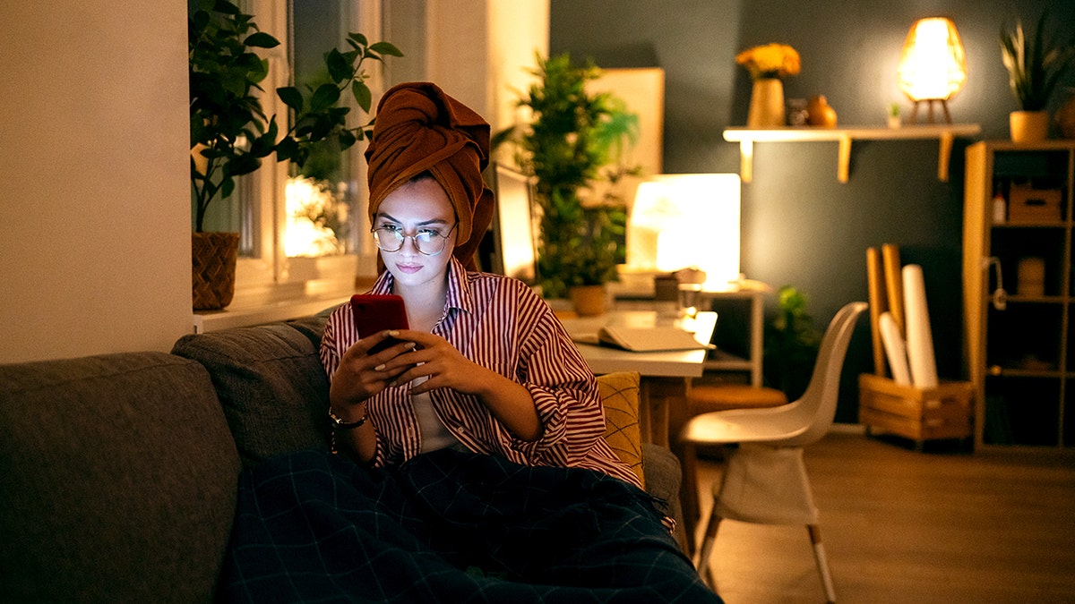 Young woman using phone during the relaxing evening at home.