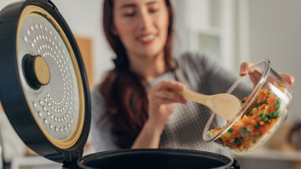 Woman dumping chopped veggies into slow cooker