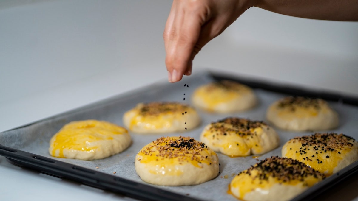 Person sprinkling black cumin while cooking