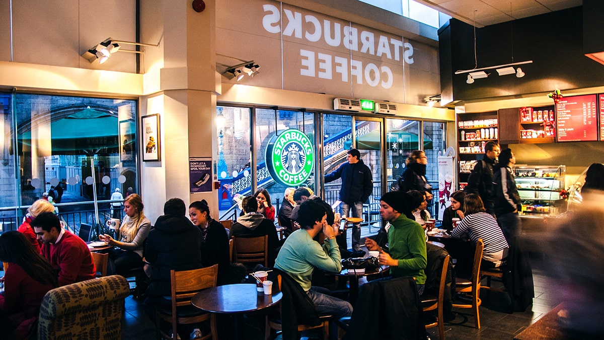 Patrons sit and socialize inside a Starbucks coffee shop.