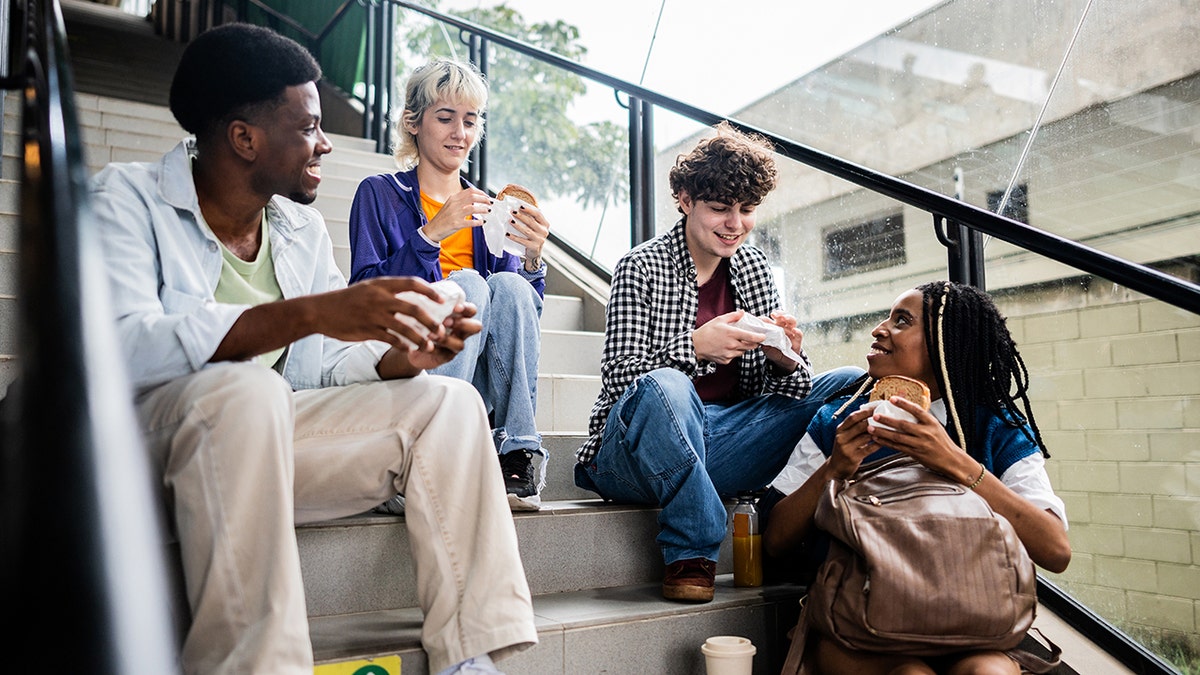 Friends drinking and eating on the stairs of the subway station