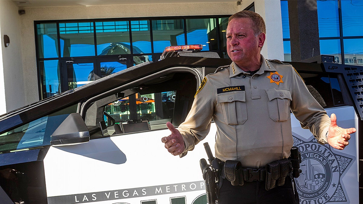 A police officer standing in front of a police Cybertruck.