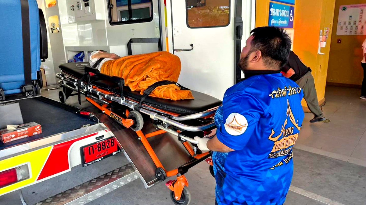 emergency personnel wheeling woman on gurney into an ambulance