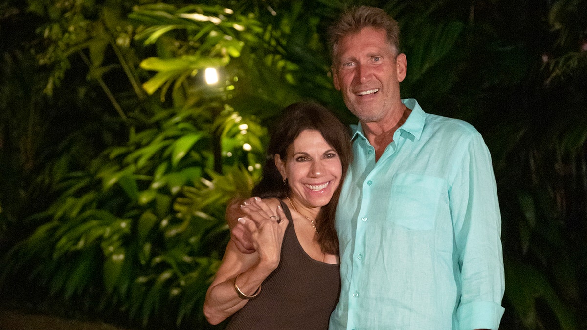Gerry Turner embracing Theresa Nist outdoors as they're both smiling.